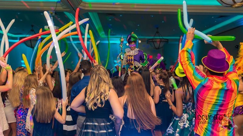 Crowd dancing with raised inflatable tubes at a colorful outdoor concert stage