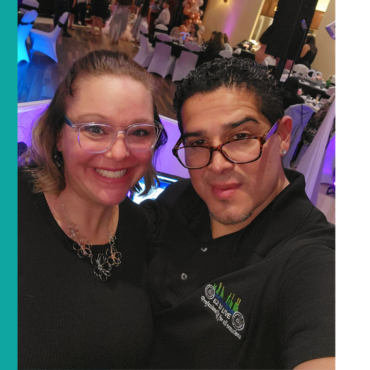 Two smiling people posing for a selfie at a decorated indoor event