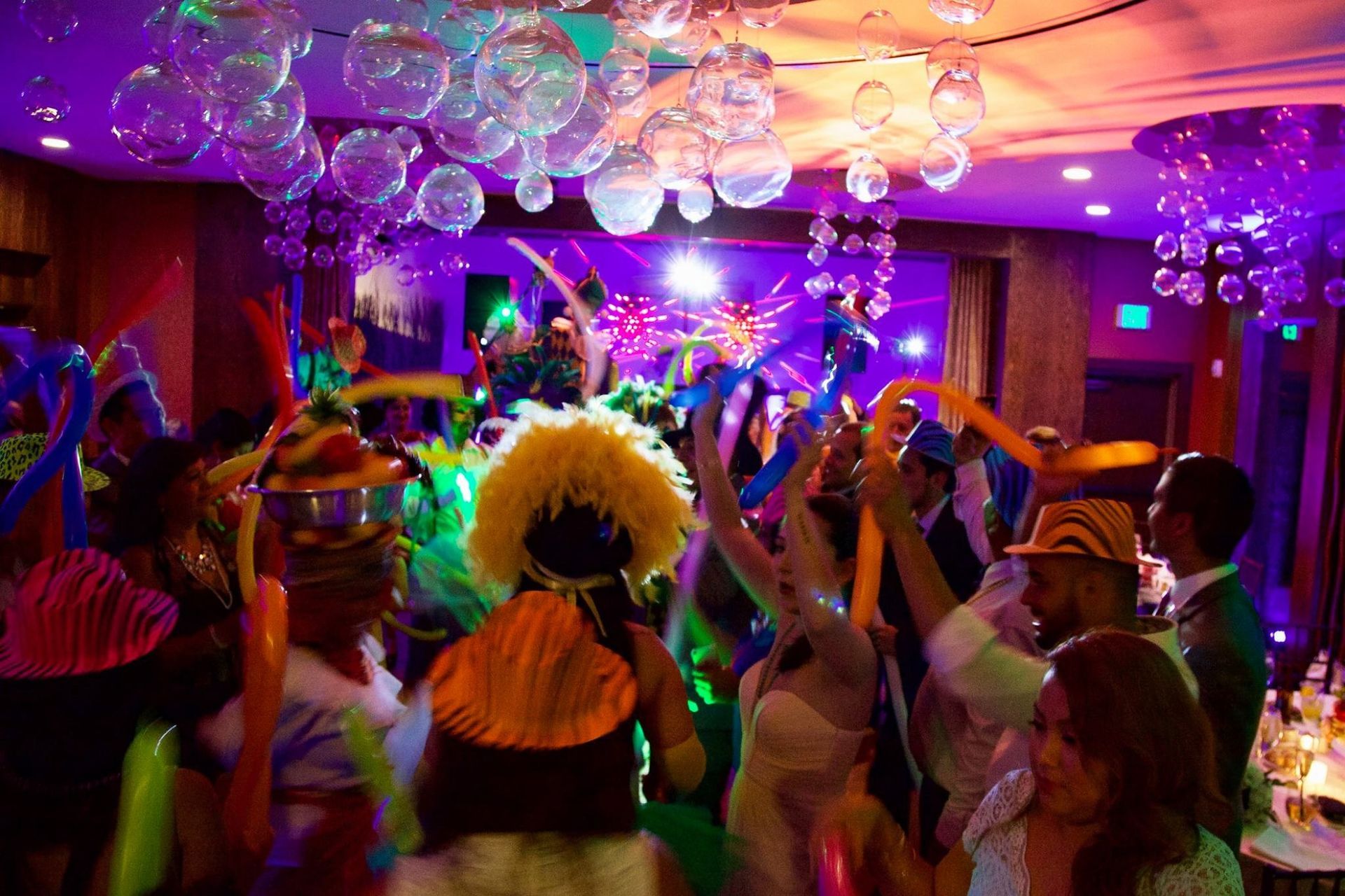 Crowded party with dancers under colorful disco lights and floating balloons