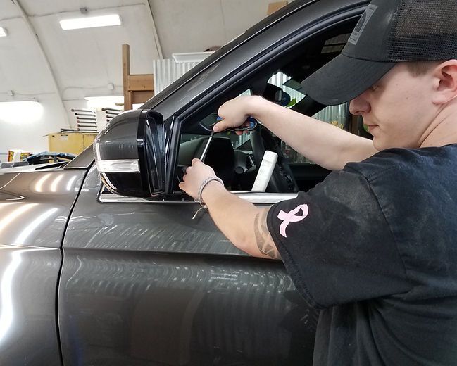 A man wearing a black hat is working on a car