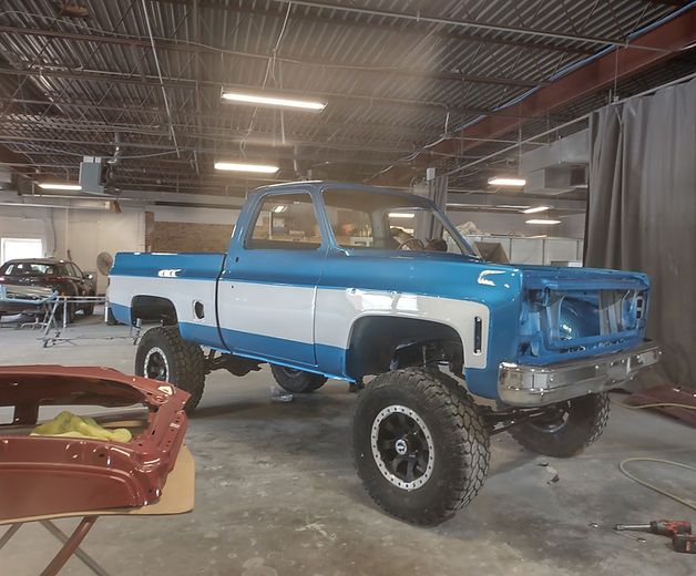 A blue and white truck is parked in a garage.