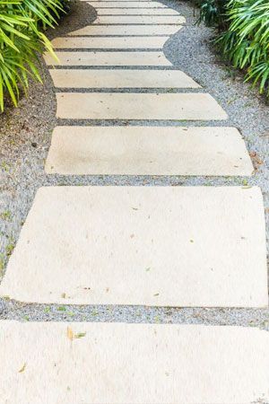 Stone pathway winding through a garden, surrounded by gravel and greenery.
