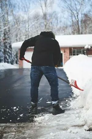 Person shoveling snow Person shoveling snow from a driveway in front of a house on a winter day.