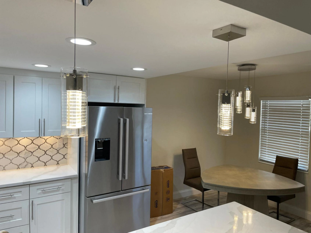 Modern kitchen with pendant lights, stainless steel appliances, and a dining area with a round table and chairs.