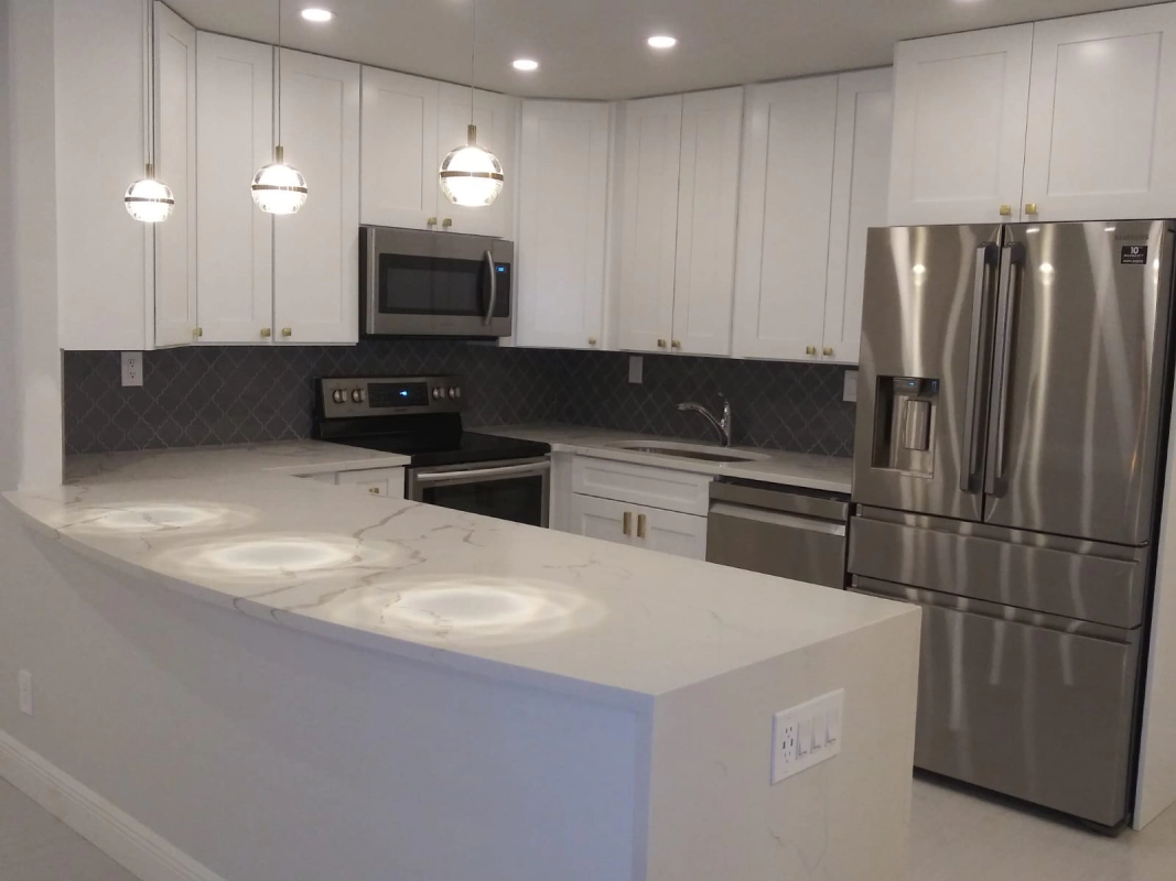 White kitchen with stainless steel appliances, white cabinets, and quartz countertops.