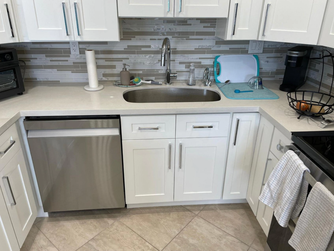 Bright kitchen with white cabinets, stainless steel appliances, and a sink area.