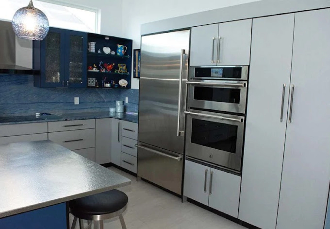 Modern kitchen with stainless steel appliances, blue and gray cabinets, and a metal island.
