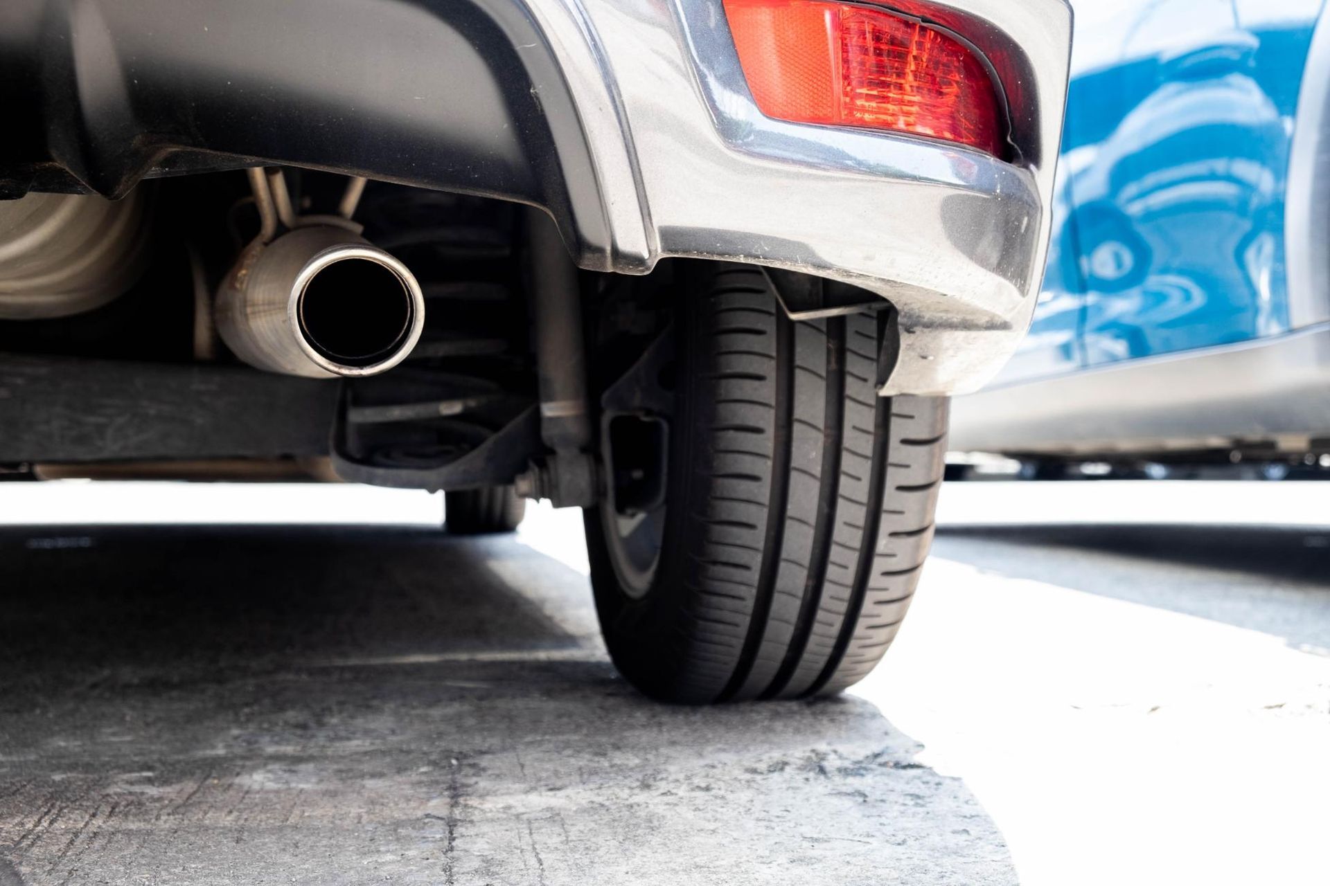A close up of the exhaust pipe of a car parked in a parking lot.