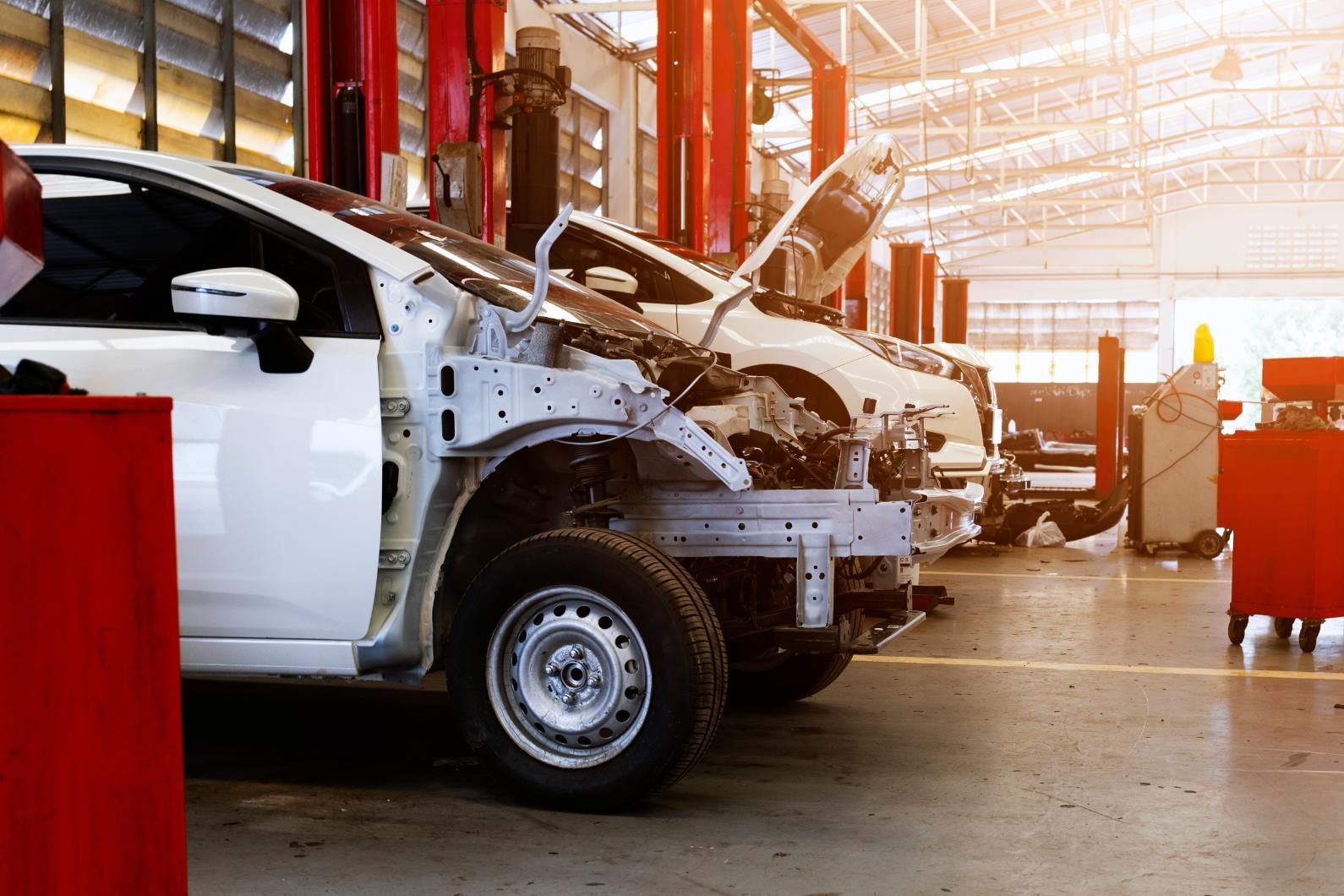 A white car is being repaired in a garage.