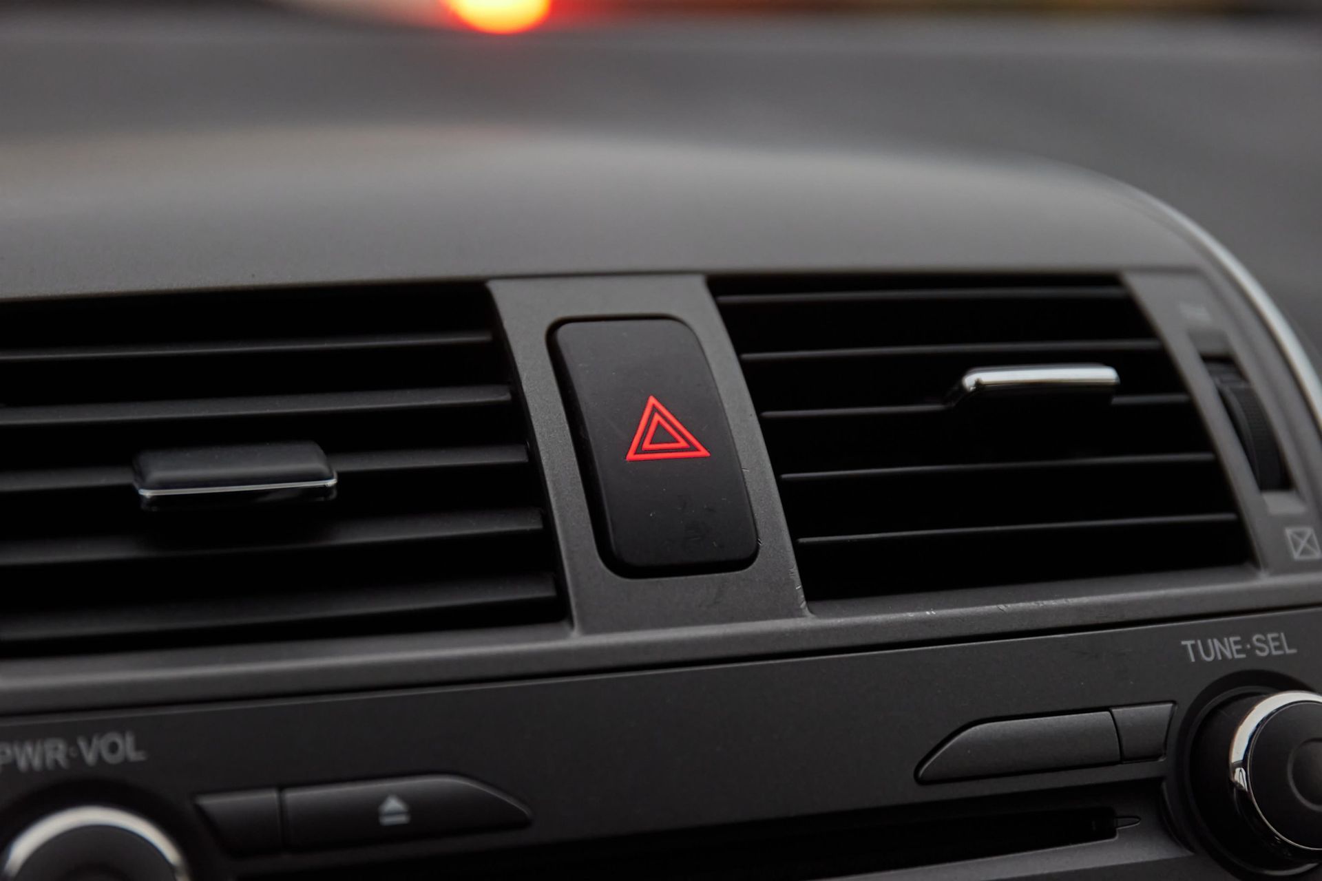 A close up of a car air vent with a red triangle on it.