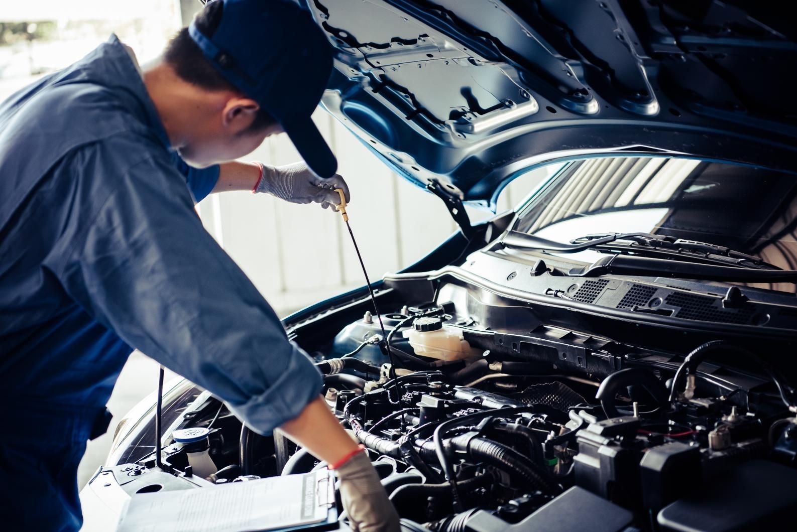 A man is working on the engine of a car with the hood open.
