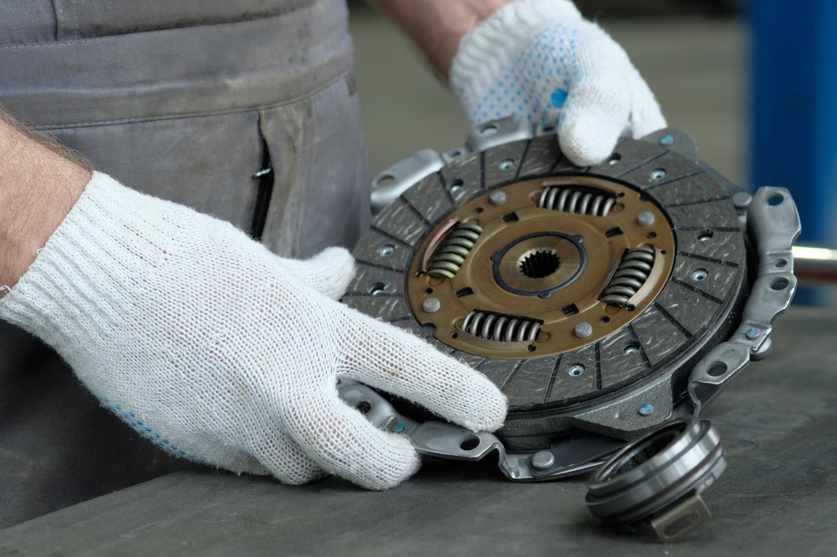 A man wearing white gloves is working on a clutch disc.