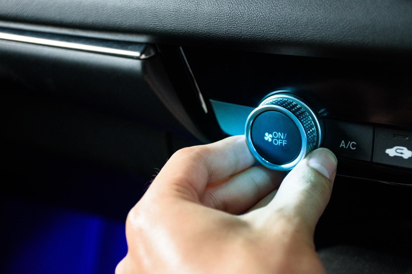 A person is adjusting the air conditioning in a car.