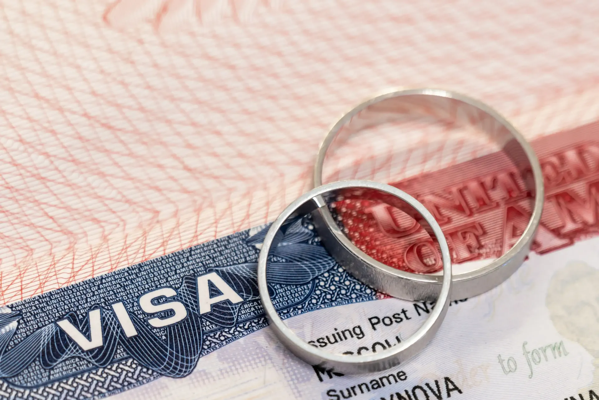 Wedding rings on top of a United States visa document.