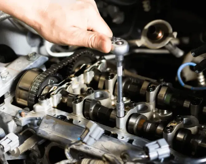 Mechanic tightening an engine bolt with a wrench in a car engine bay