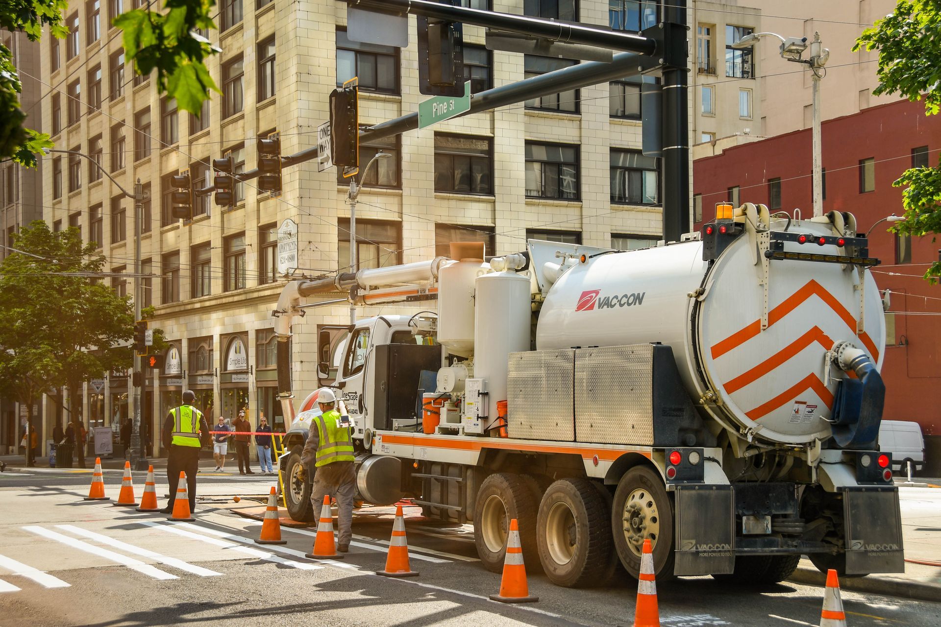 A vacuum truck is parked on the side of a city street.