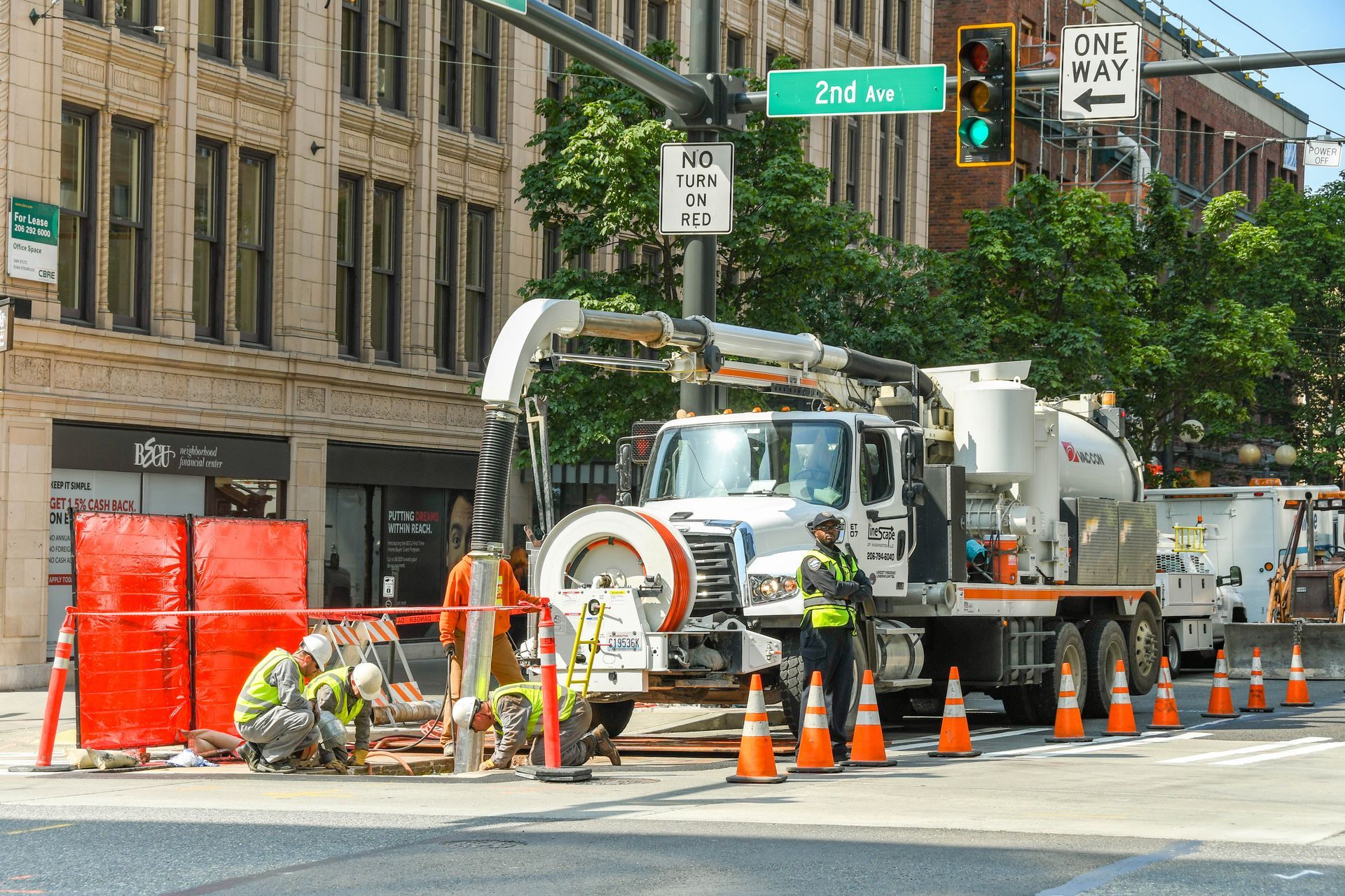 A construction truck is driving down a city street next to a one way sign.