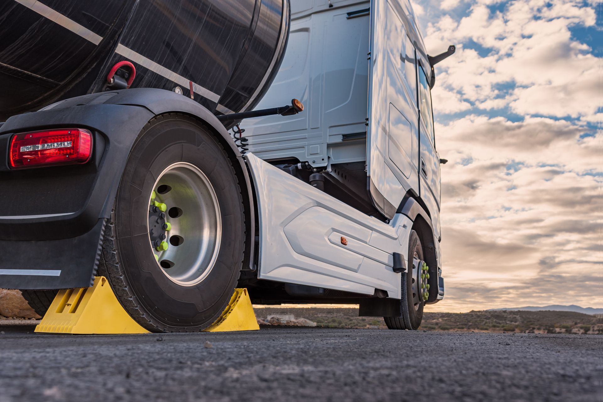 A semi truck is parked on the side of the road next to a yellow block.