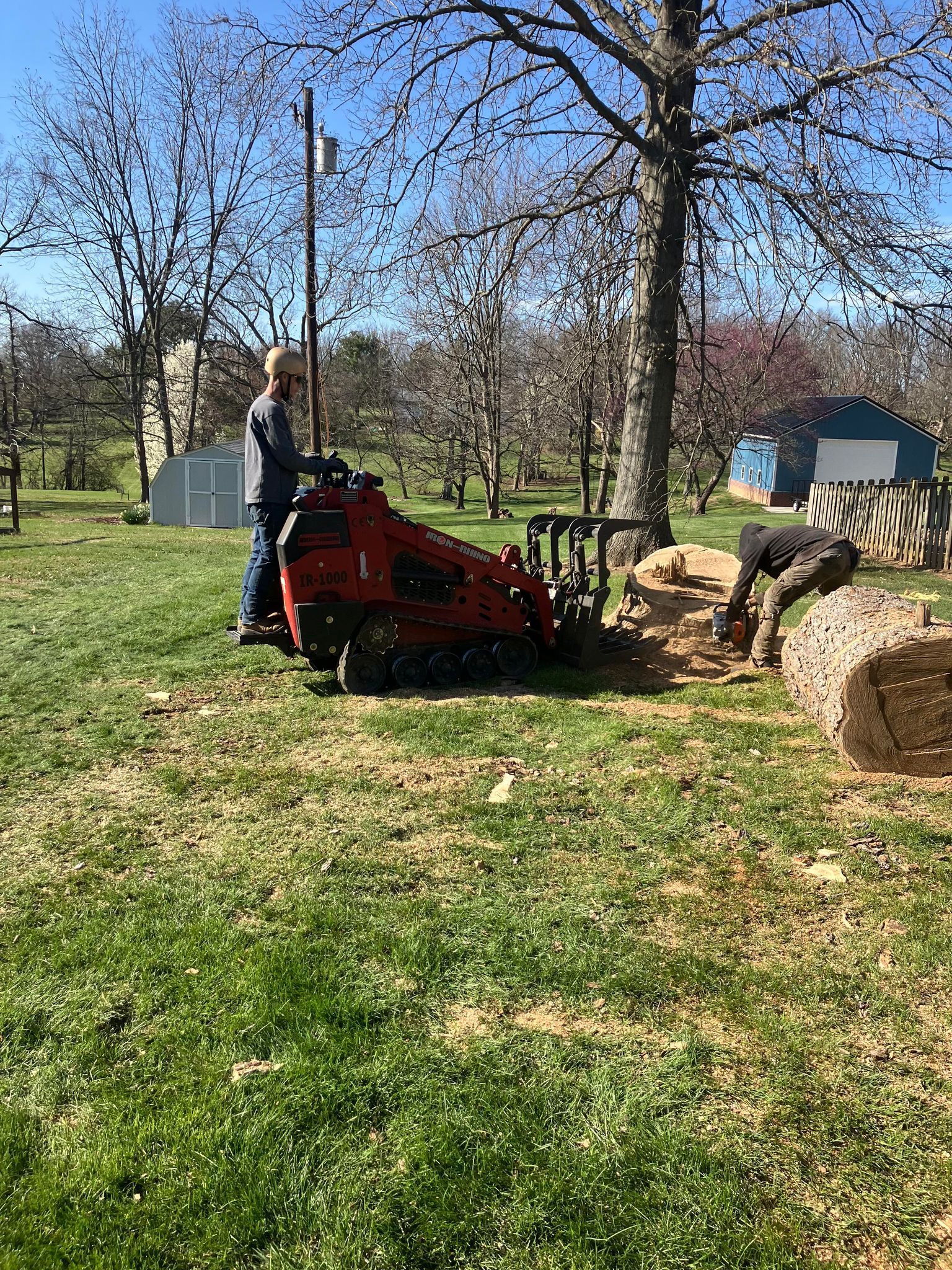 A man is using a machine to remove a tree stump.