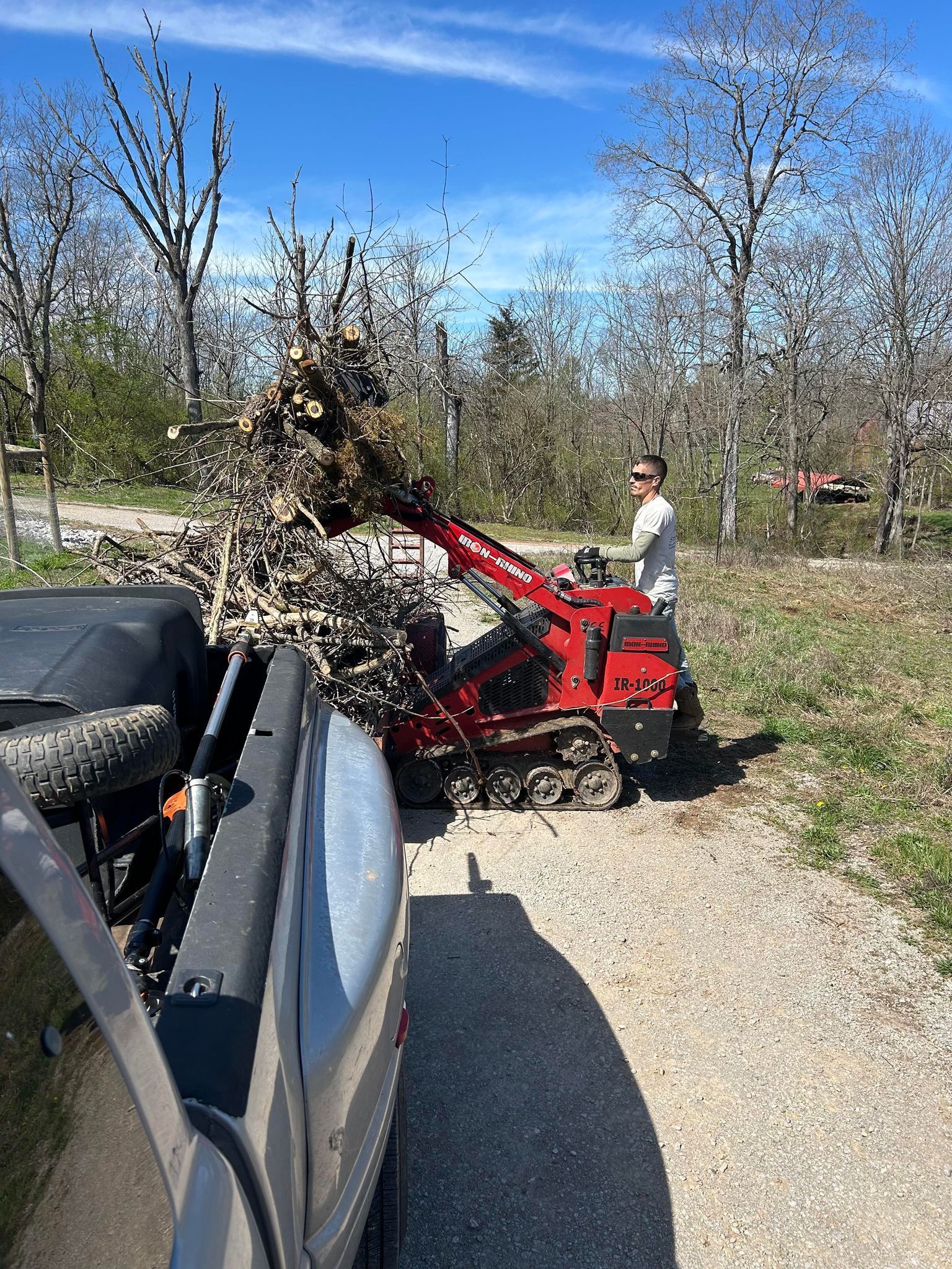 A man is using a tractor to remove branches from a tree.