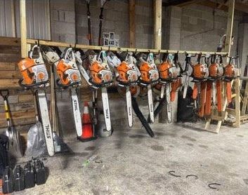 A bunch of chainsaws are hanging on a rack in a room.