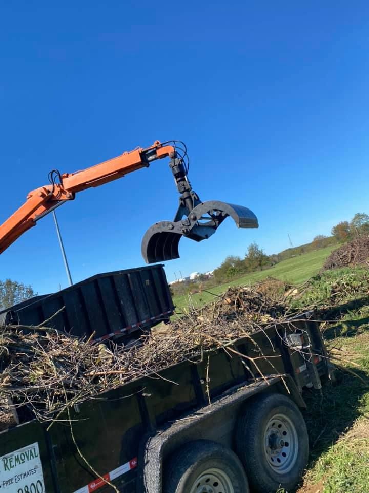A crane is loading a dumpster into a trailer.