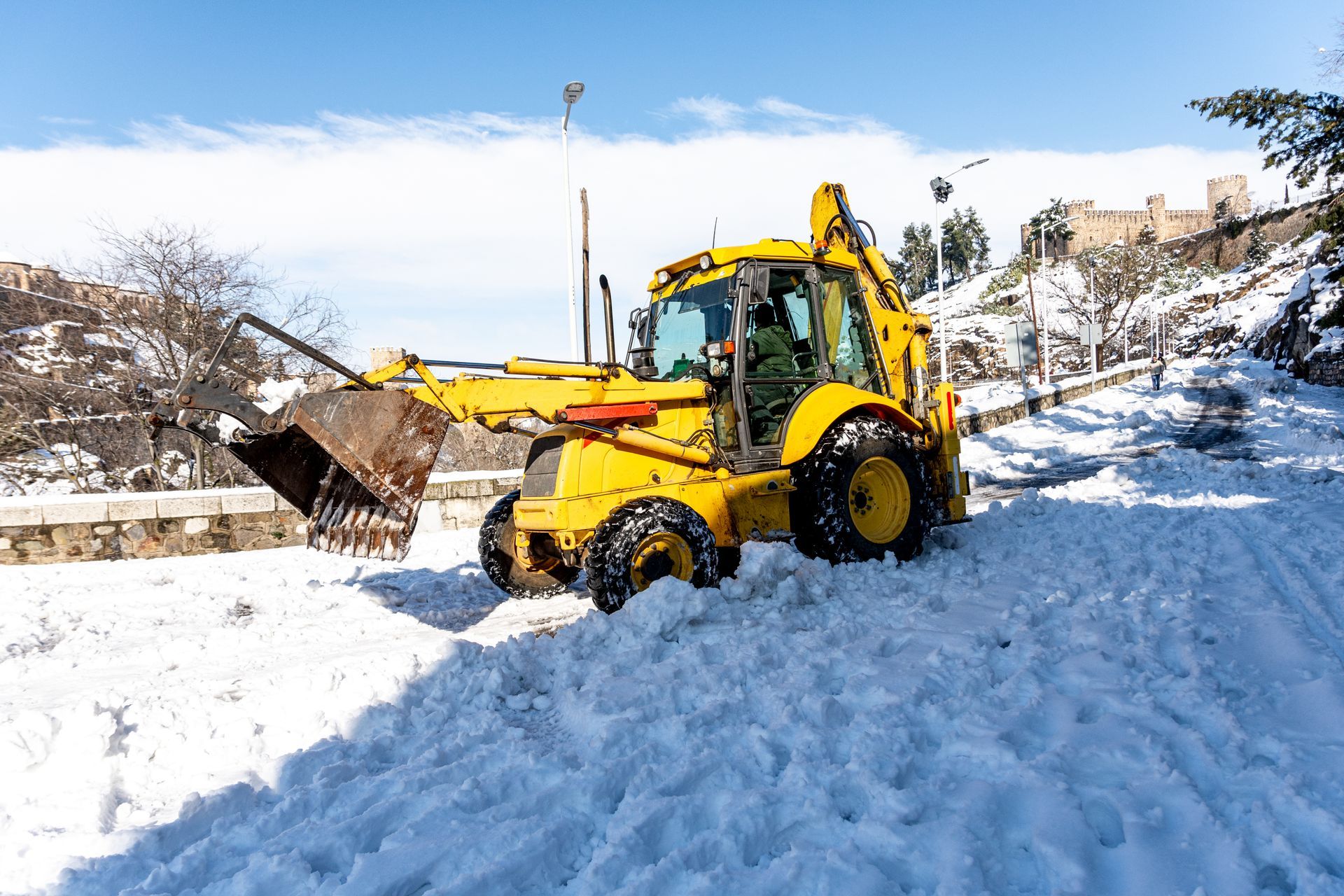A yellow bulldozer is clearing snow from a road.