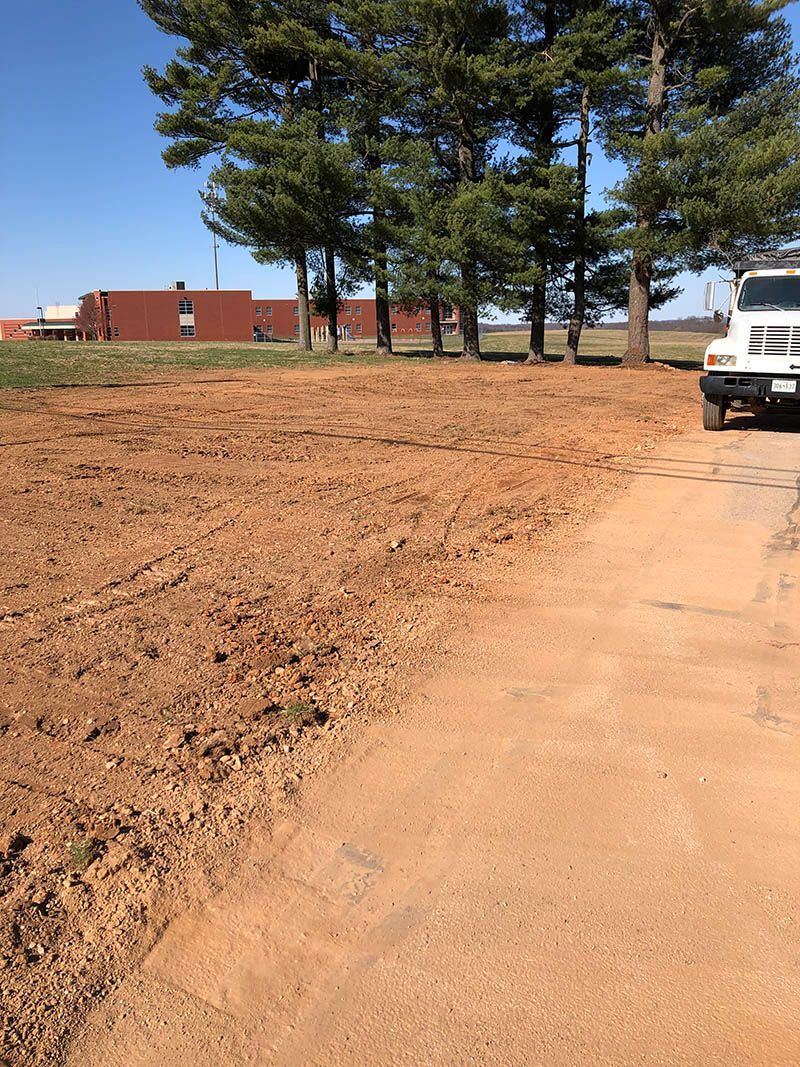 A white truck is parked on the side of a dirt road.