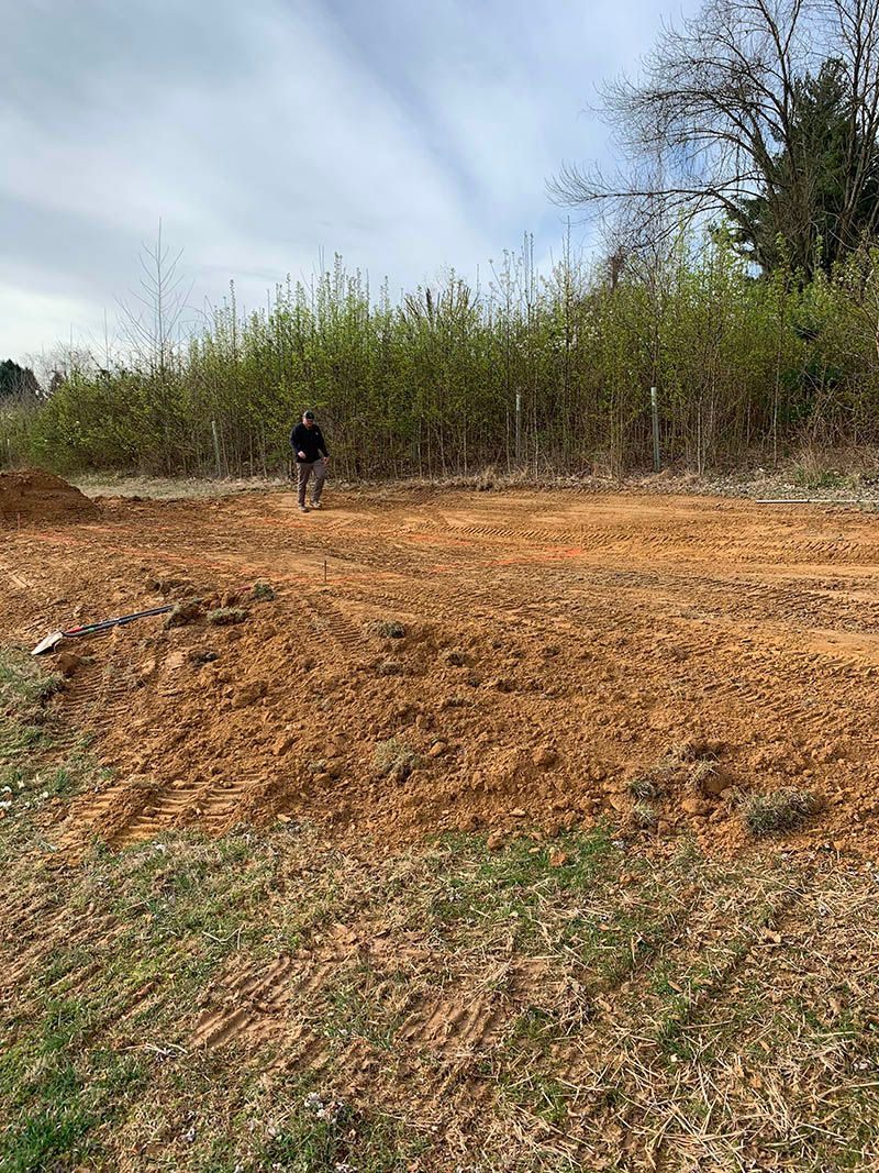 A man is standing in the middle of a dirt field.