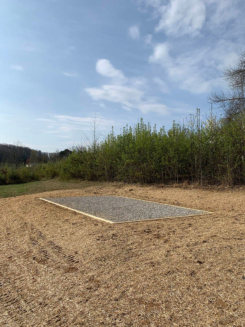 A large pile of gravel is sitting in the middle of a field.