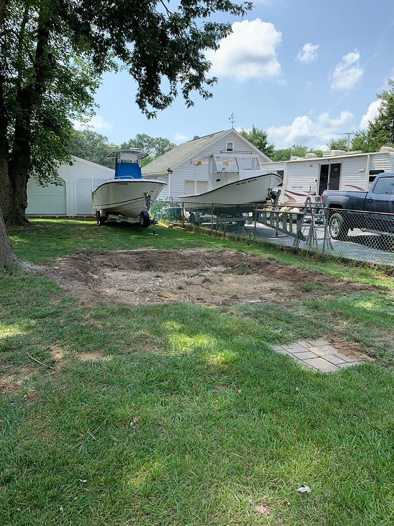 A couple of boats are parked in the grass in front of a house.