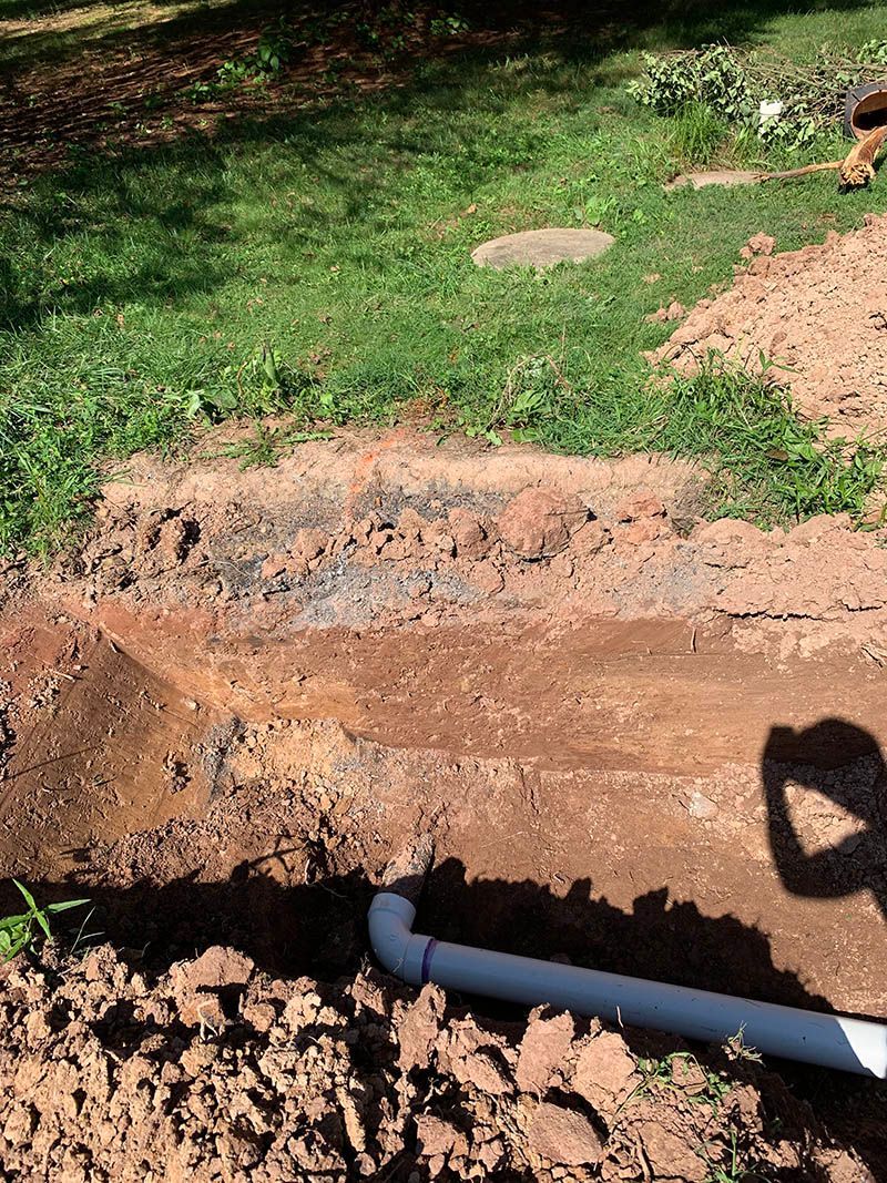 A pipe is being installed in the dirt in a yard.