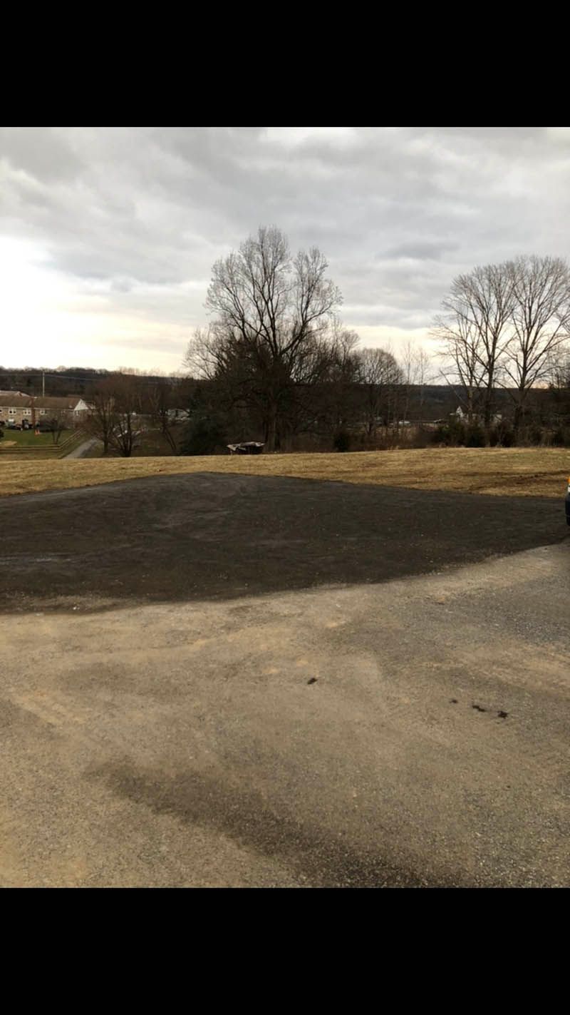 A car is parked in a parking lot with trees in the background.