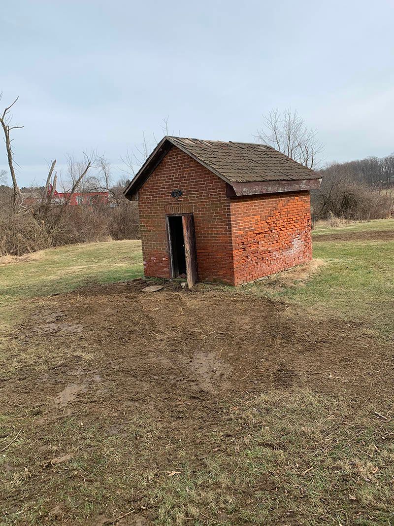 An old brick building is sitting in the middle of a field.