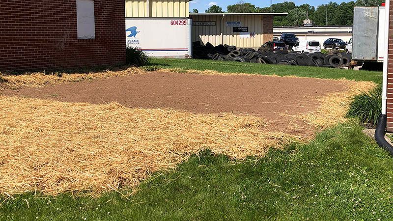 A brick building is sitting in the middle of a grassy field.