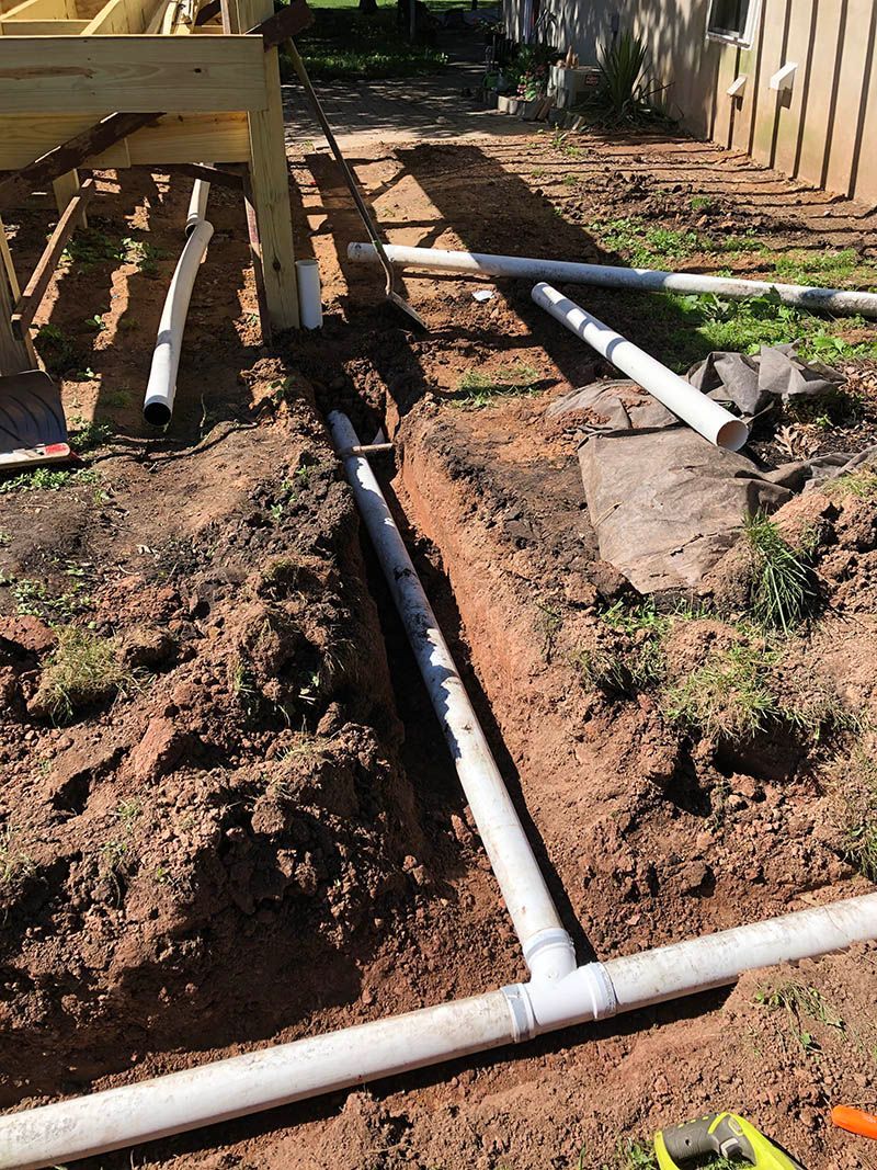 A bunch of white pipes are laying in the dirt.