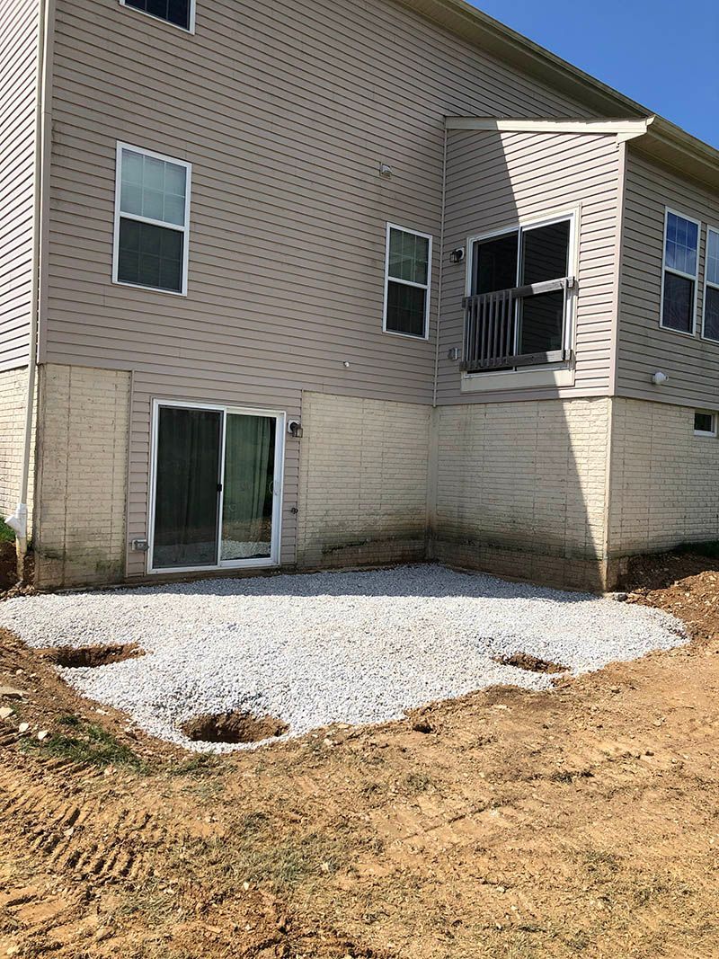 The back of a house with a patio in front of it.