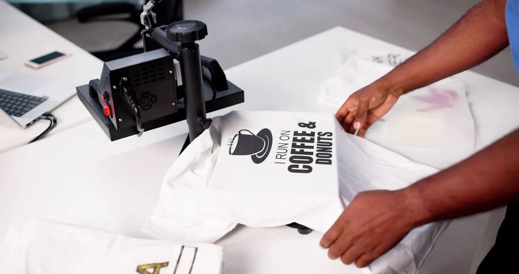 Hands arranging a white T-shirt with black printed text on a heat press table Hands arranging a white T-shirt with black printed text on a heat press table