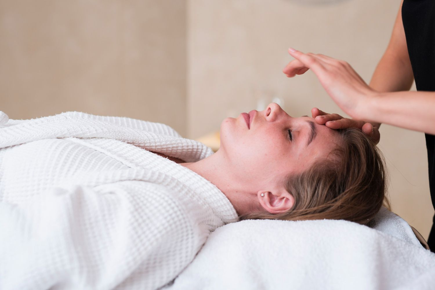A woman is laying on a bed getting a facial massage.