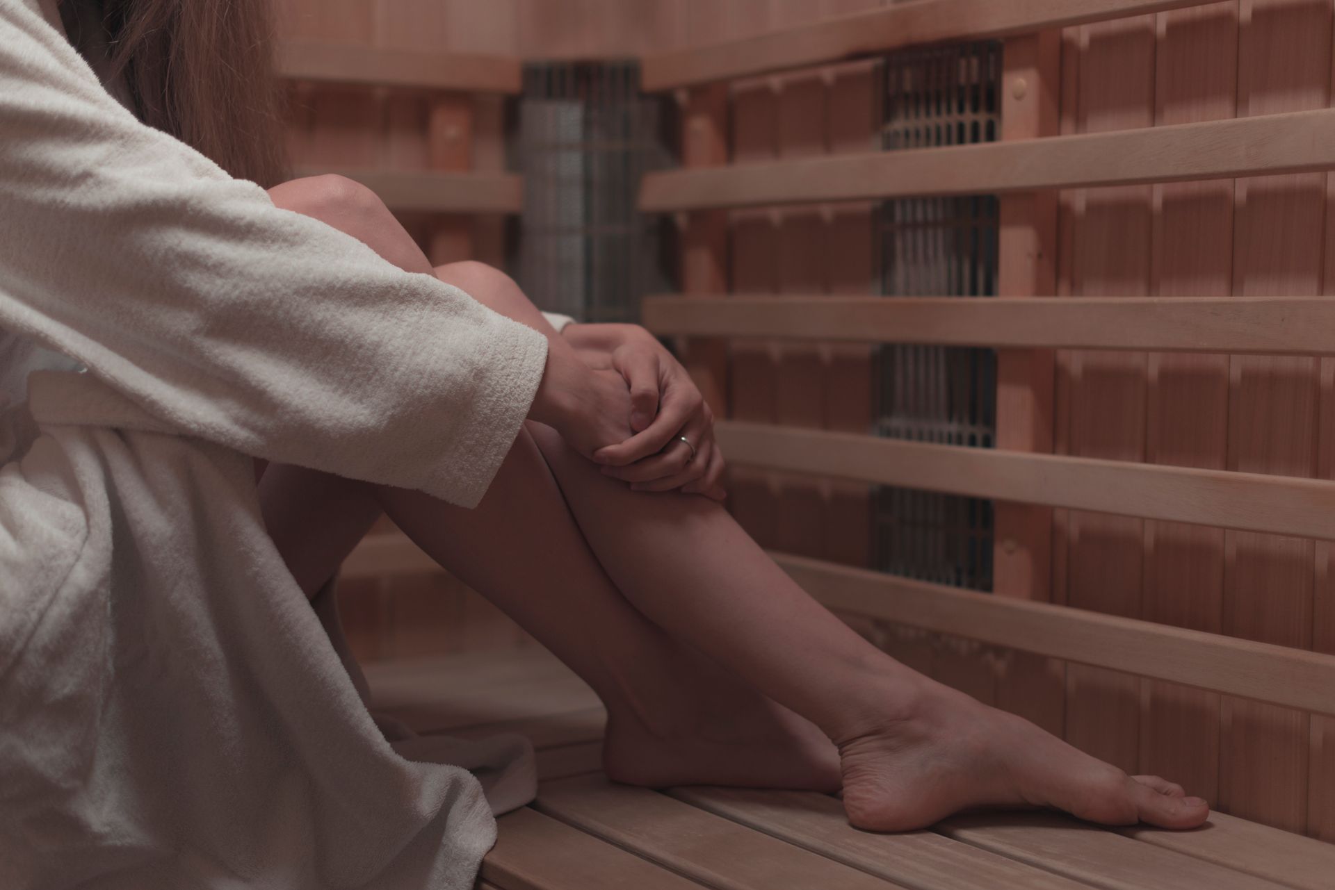 A woman is sitting in a sauna with her legs crossed.