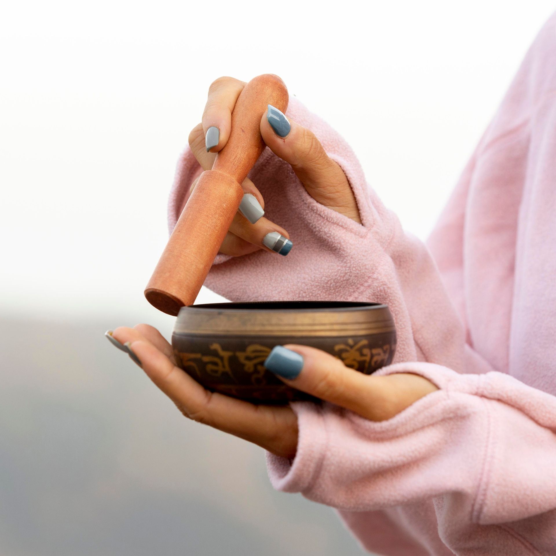 A woman is holding a bowl with a wooden stick in her hands.
