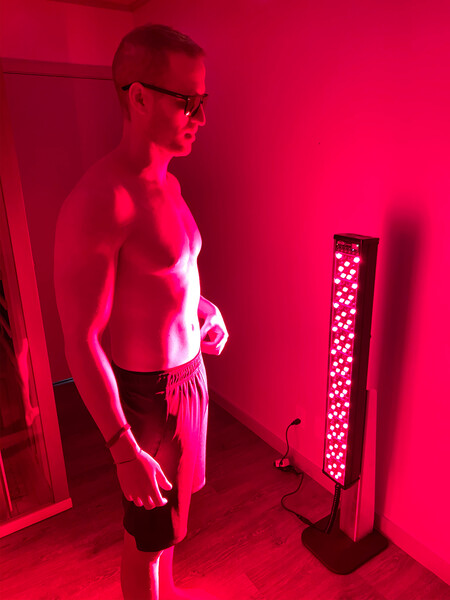 A shirtless man is standing in front of a red light