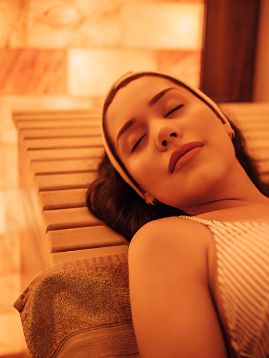 A woman is laying on a wooden chair with her eyes closed.