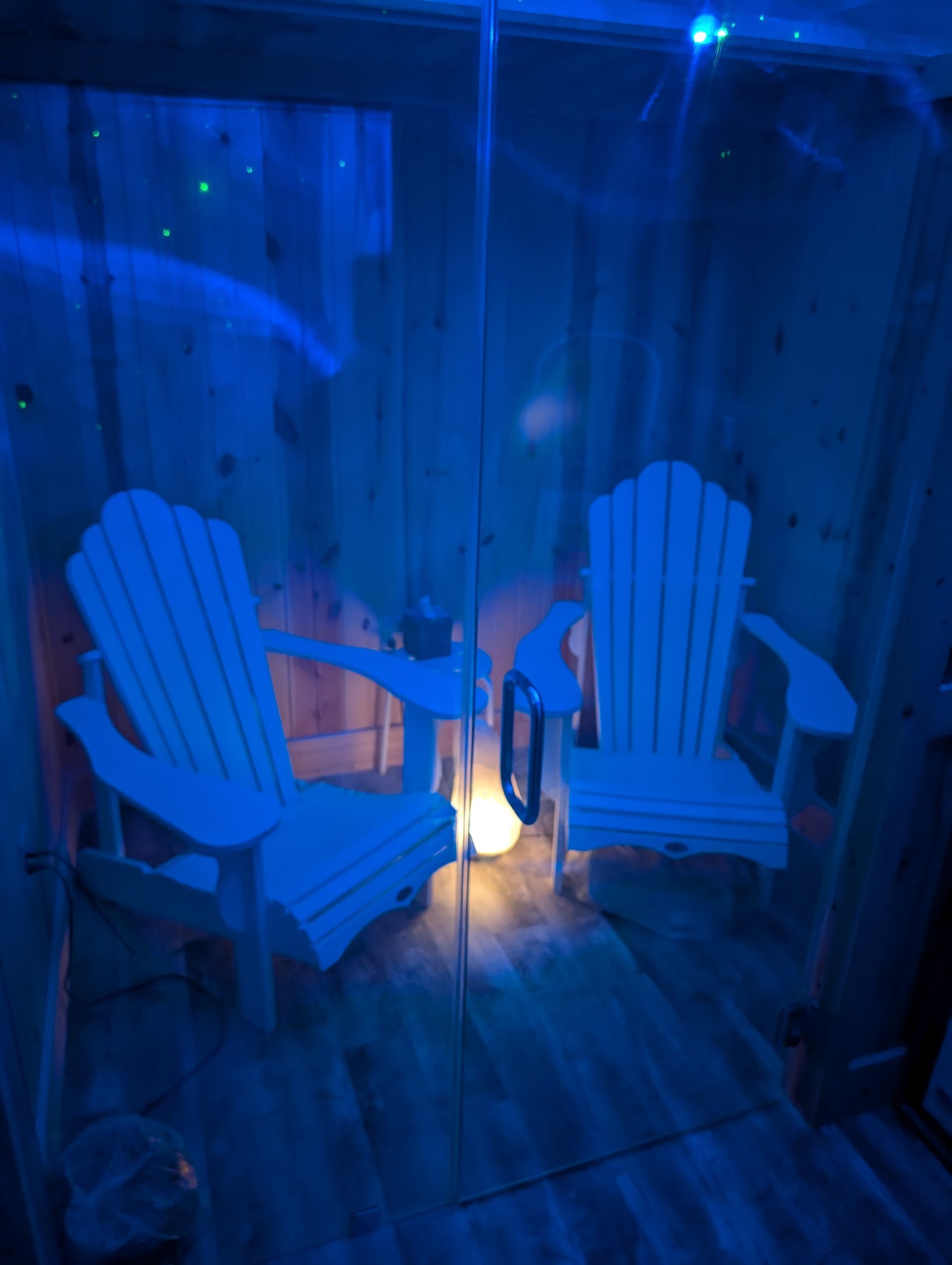 Two white adirondack chairs in a dark room with blue lights