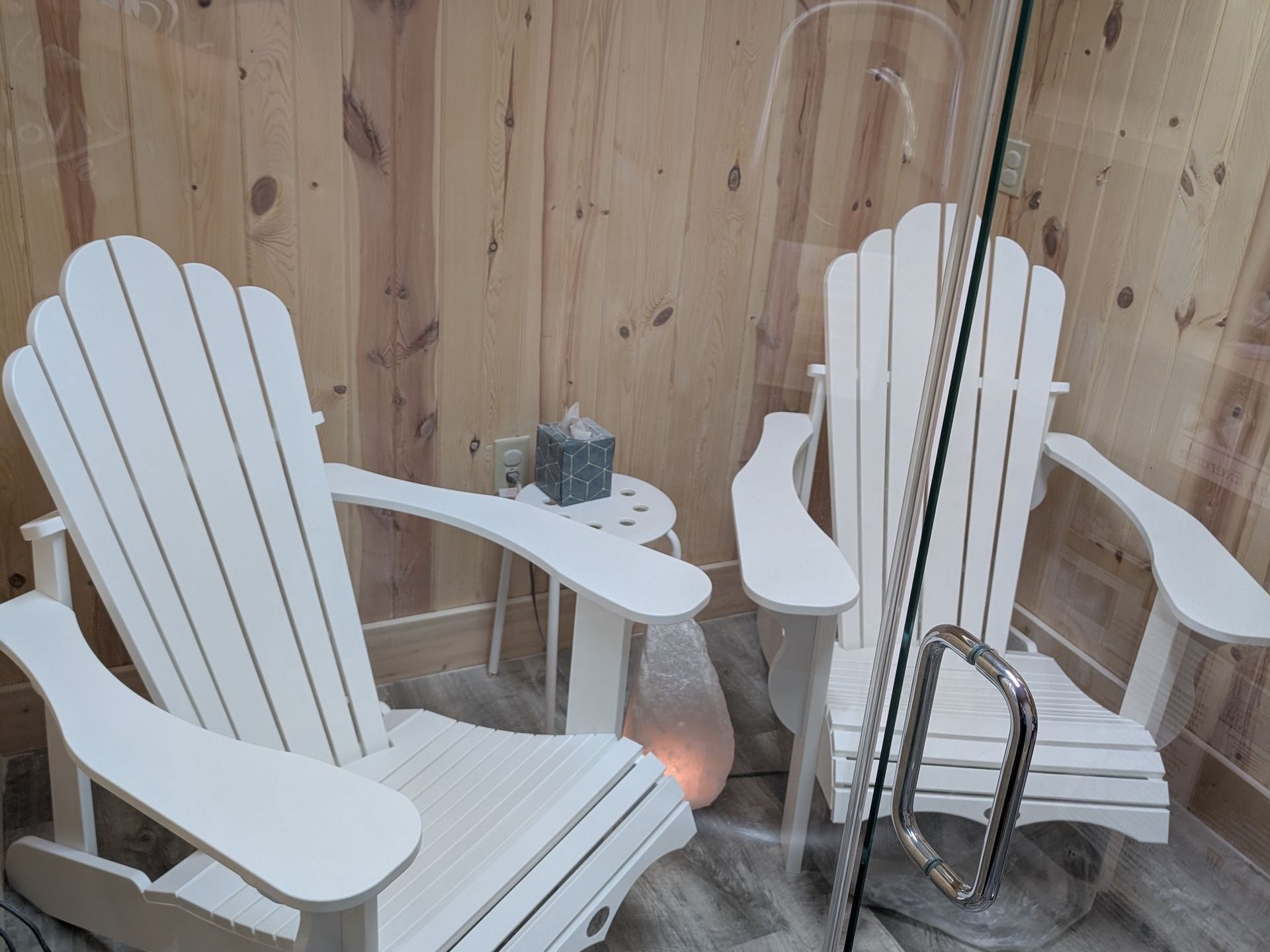 Two white adirondack chairs are sitting next to each other in a room.