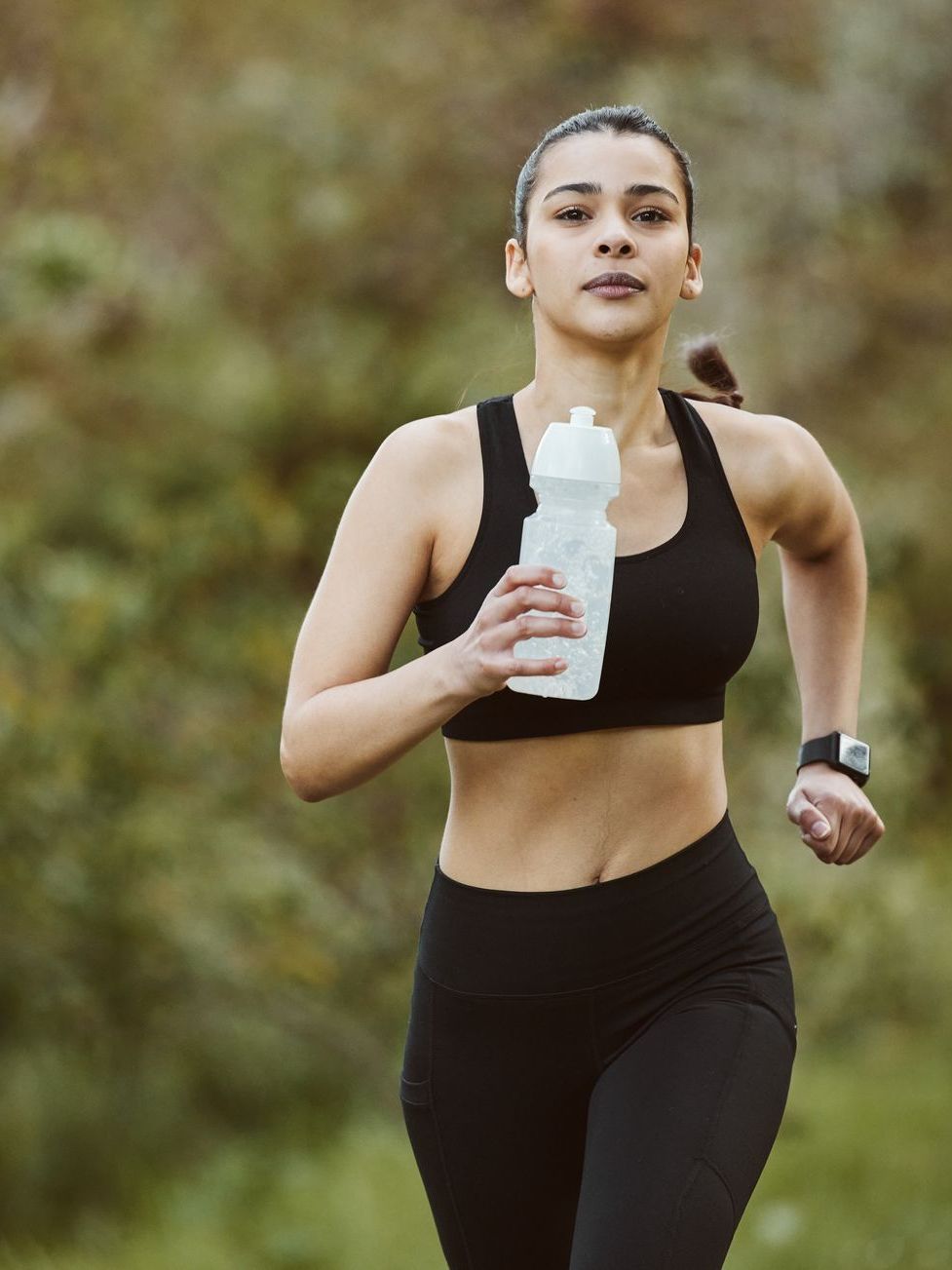A woman is running with a water bottle in her hand.