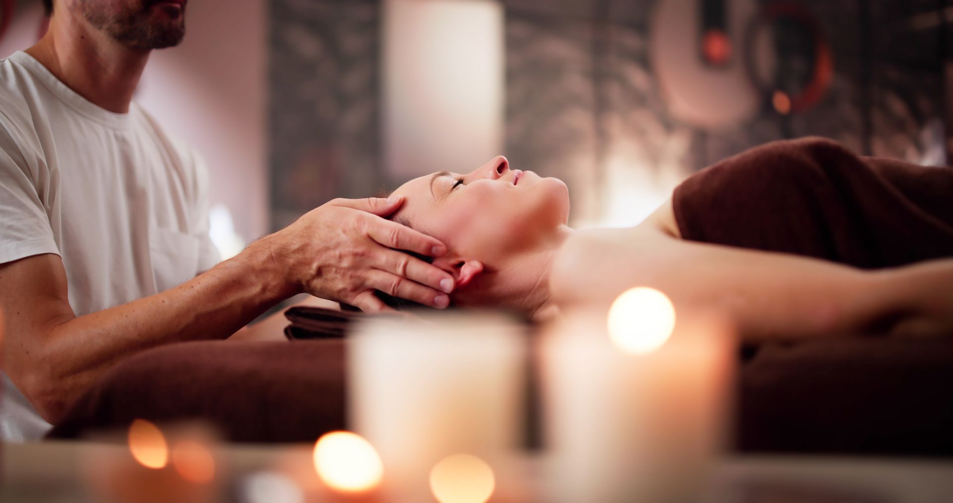 A woman is getting a massage at a spa with candles in the background.