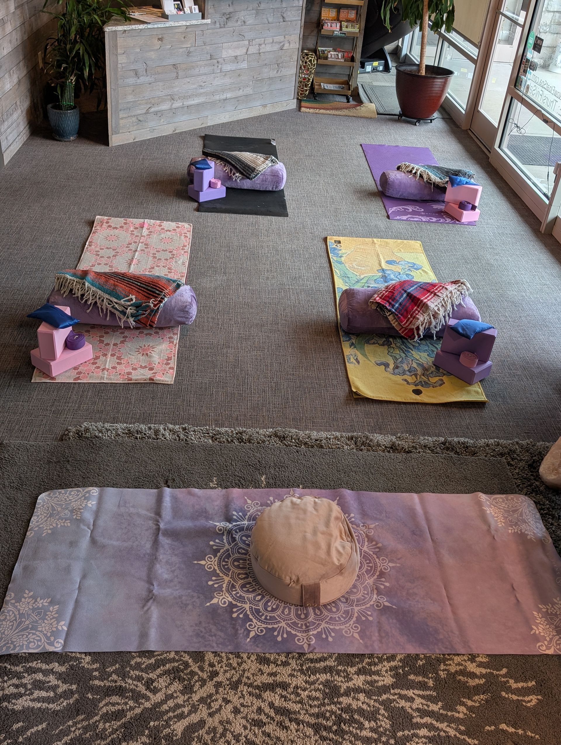 A room with a lot of yoga mats and pillows on the floor.