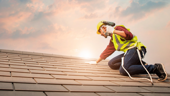 A man is working on a roof with a drill.