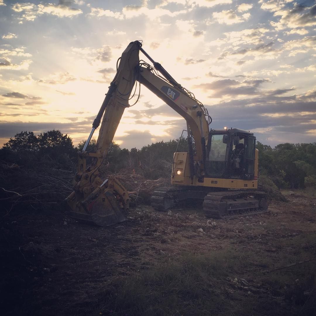 Woman in straw hat smiles, holding wine glass near a lake.